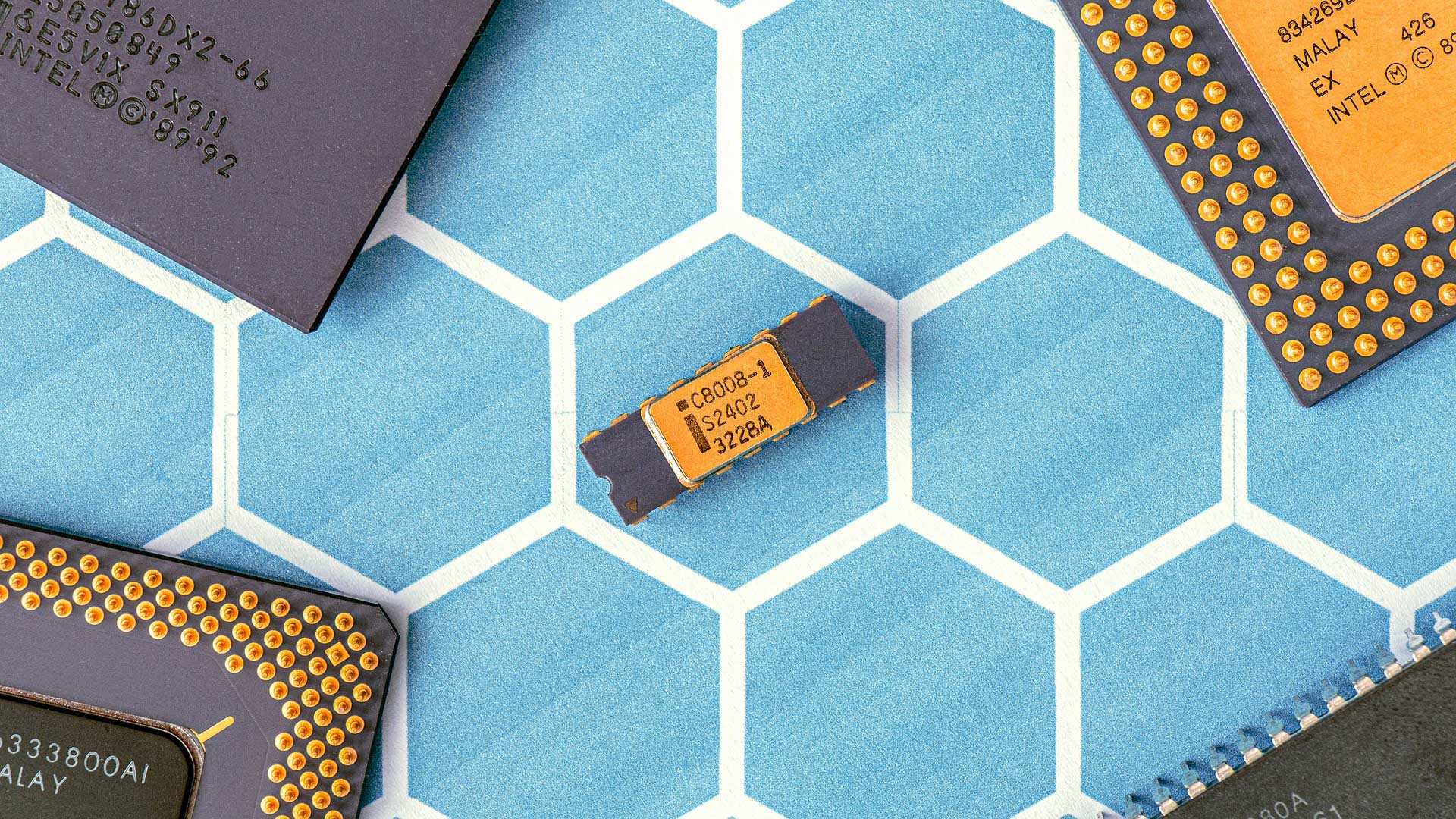Computer chips and microprocessors arranged on a blue hexagonal patterned surface, showcasing various electronic components with visible pins and markings.