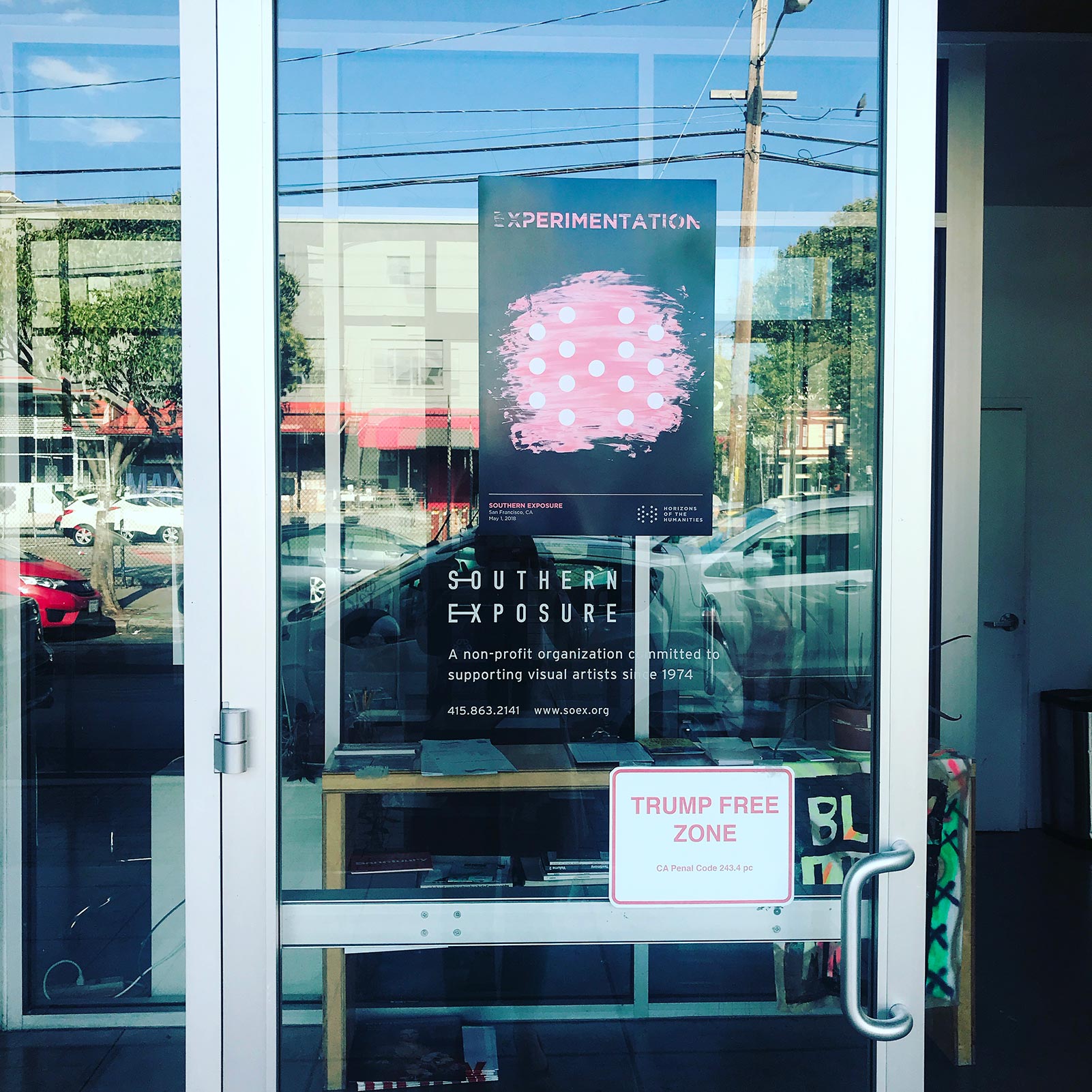 An event poster is plastered on a glass door above a sign that states "Trump Free Zone"
