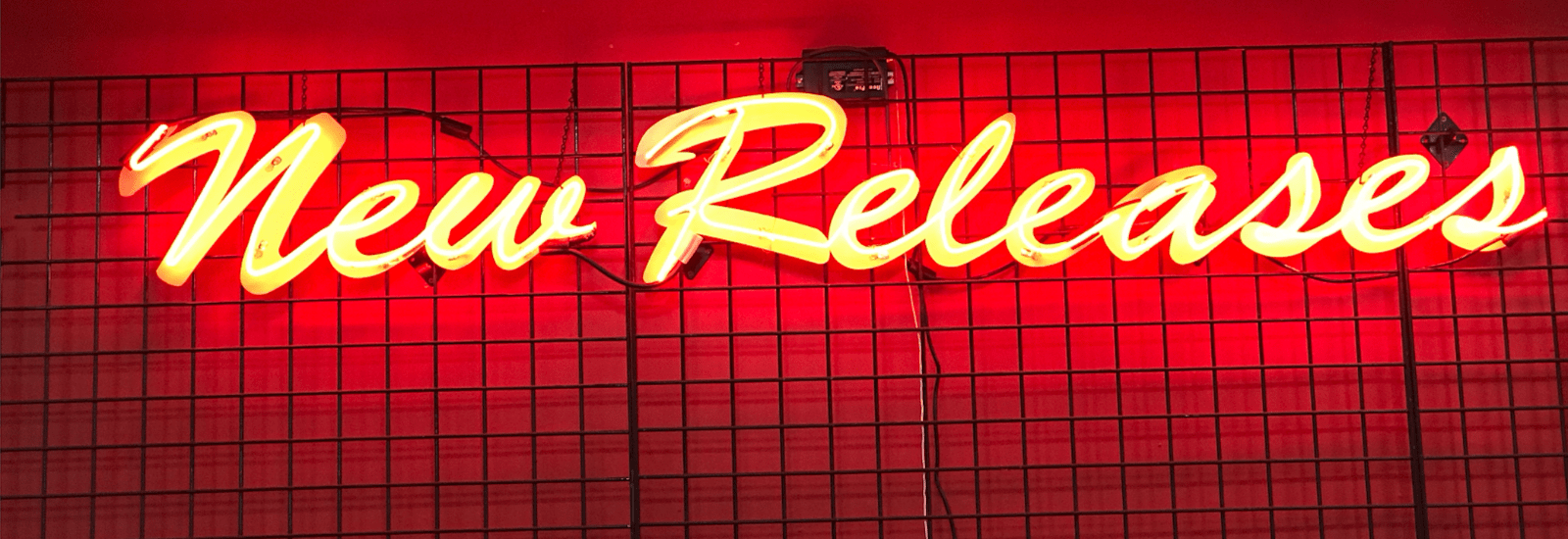 Neon sign reading “New Releases” in an adult video store, with a small portion of DVD cases visible below it.